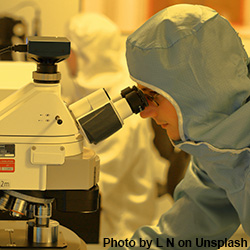 scientist looking thru microscope for vaccine
