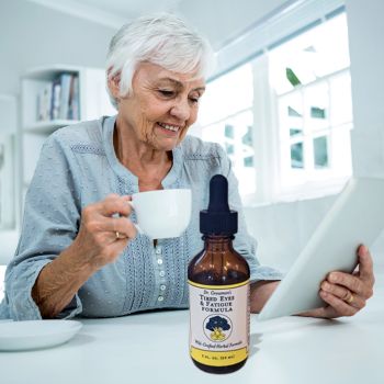 woman drinks a tincture for digital eye strain while reading a computer tablet