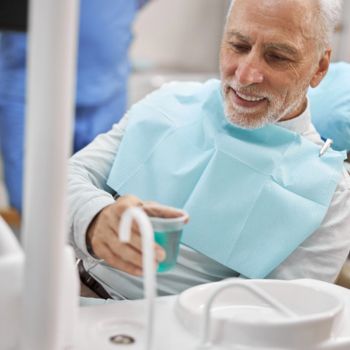 a senior man rinsing out oral bacteria at the dentist's office