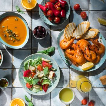 Food prominent in the Mediterranean Diet including salmon, greens, fruits and vegetables, olives.