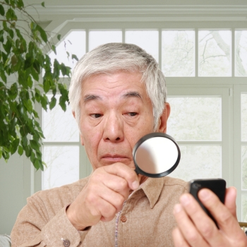 Man has Presbyopia and needs a magnifying glass to read his phone